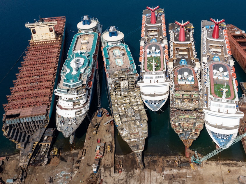 caption: In this aerial view, five luxury cruise ships are seen being broken down for scrap metal in Izmir, Turkey. With the global coronavirus pandemic pushing the cruise industry into crisis, some cruise operators have been forced to cut losses and retire ships. The cruise industry has been one of the hardest hit industries after a series of outbreaks occurred on cruise liners as the pandemic spread.