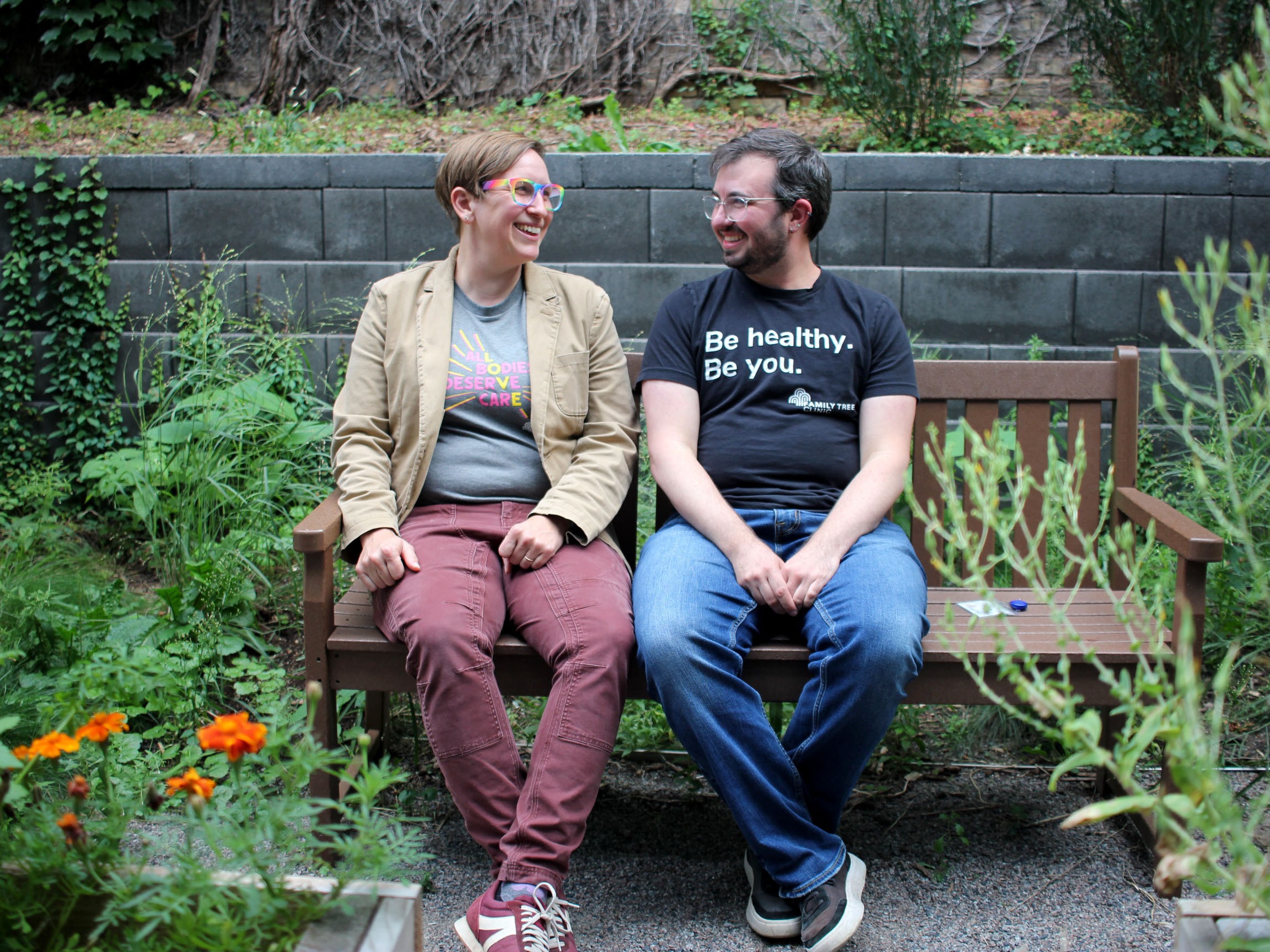 caption: Dr. Kelsey Leonardsmith (left) with colleague Dylan Flunker in the garden of Family Tree Clinic in Minneapolis. The two run a program to train more doctors and nurses in the region to be able to provide gender affirming care, which is legal in Minnesota, but banned for youth in dozens of states around the country.