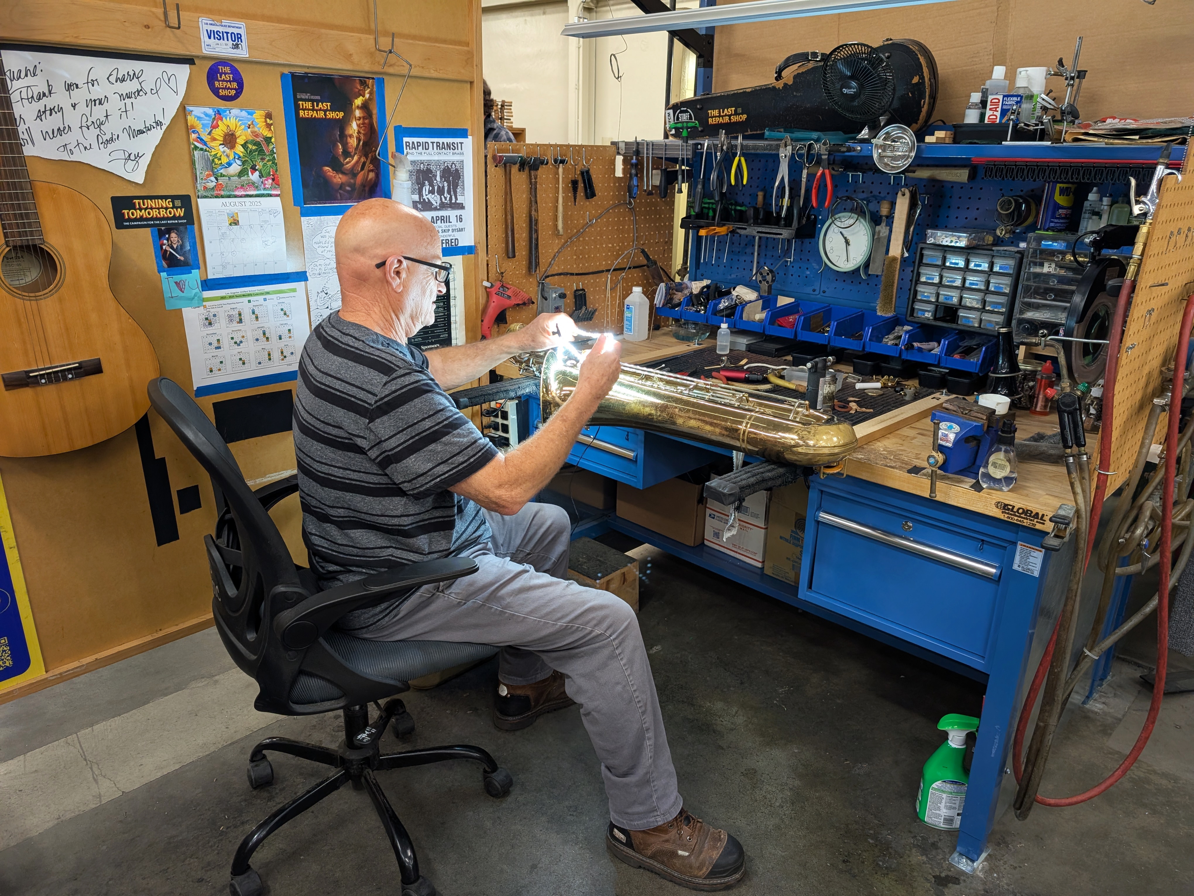 caption: Repair technician Duane Michaels solders a dented saxophone for an LAUSD student. He specializes in woodwind instruments.
