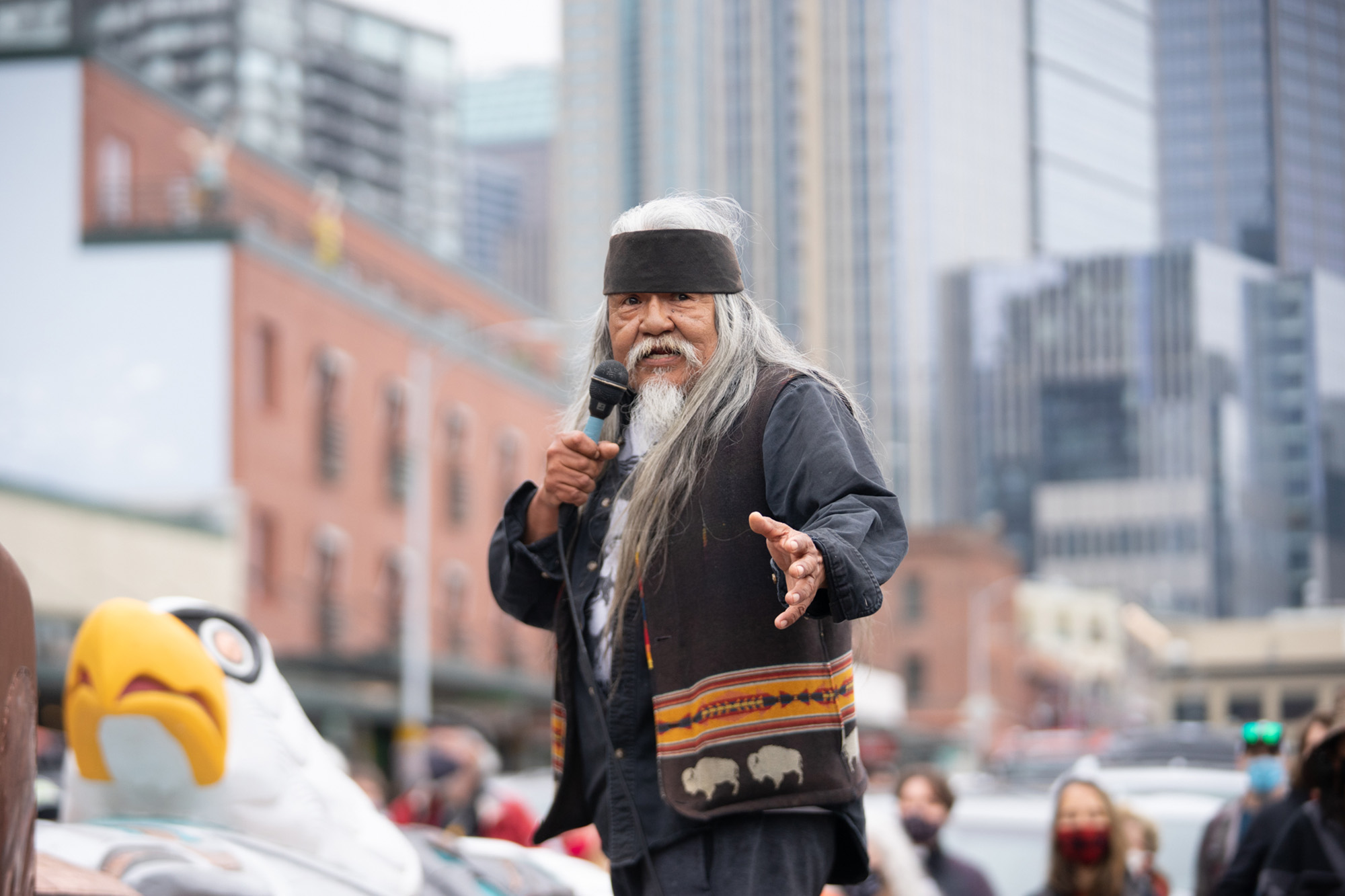 caption: Seattle’s master woodcarver Rick Williams addresses a crowd gathered around the the 24-foot totem pole at Seattle’s Pike Place Market on Saturday, May 22, 2021, in Seattle. The Williams family carvers have sold their traditional Nitinat-style art near the Seattle waterfront for at least 100 years. 
