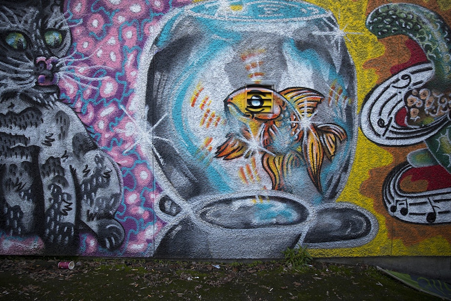 caption: A mural painted by Dylan Keene is shown on Thursday, December 6, 2018, along the backside of stores and restaurants on Lake City Way Northeast in Seattle.