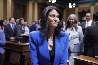 caption: Michigan Attorney General Dana Nessel walks to her seat before the State of the State address on Jan. 25 at the state Capitol in Lansing, Mich.