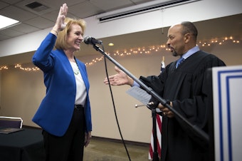 caption: Seattle mayor Jenny Durkan takes the oath of office, administered by U.S. District Court Judge Richard Jones, right, on Tuesday, November 28, 2017, at the Ethiopian Community Center in Seattle. 