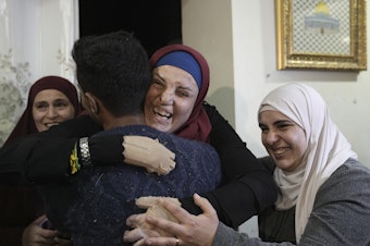caption: Israa Jaabis, center, a Palestinian prisoner released by Israel, is hugged by relatives as she arrives home in the east Jerusalem neighborhood of Jabel Mukaber, early Sunday Nov. 26, 2023.