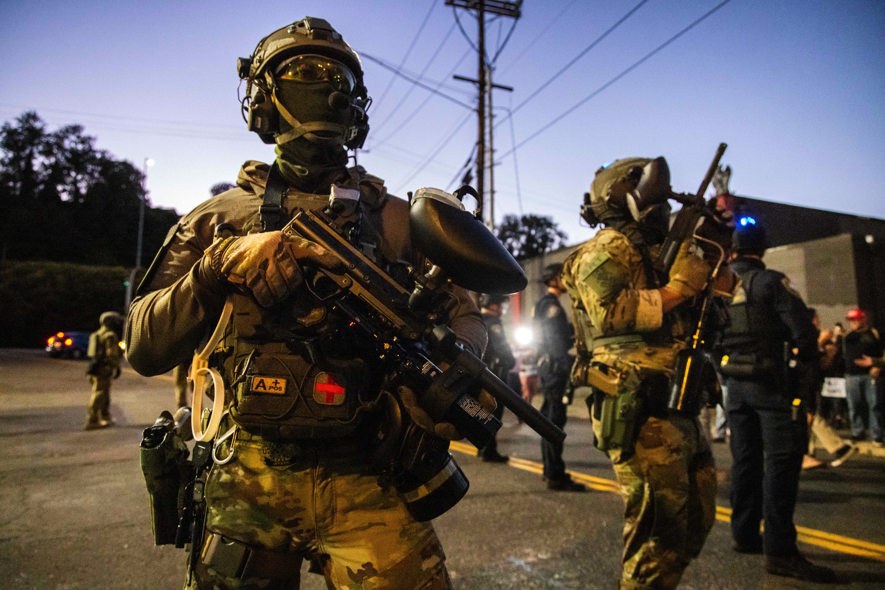 caption: Federal enforcement officers stand guard near a U.S. Immigration and Customs Enforcement facility in Portland, Oregon, Monday, Oct. 6, 2025. 