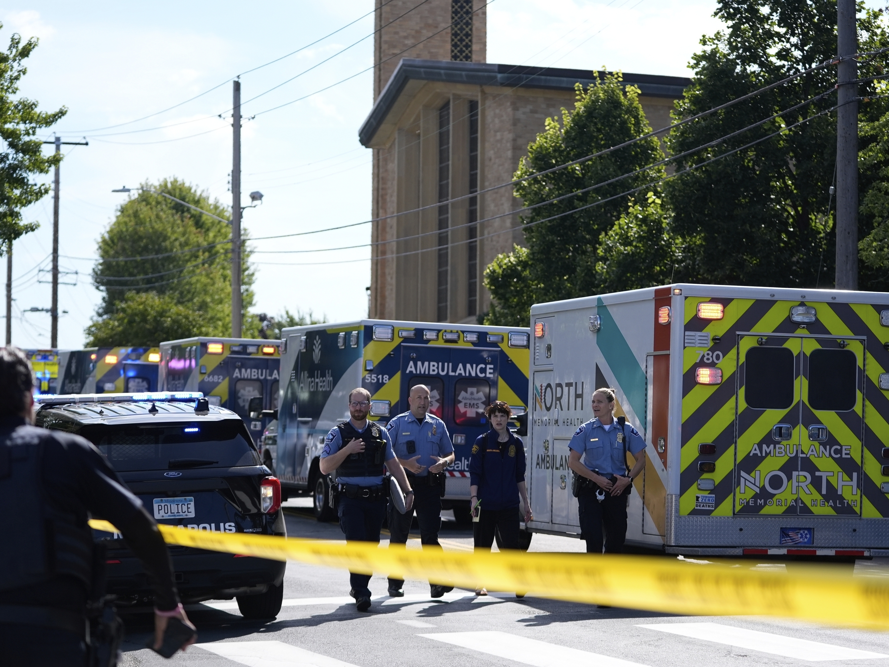 caption: Law enforcement officers gather outside the Annunciation Church School in response to a reported mass shooting on Wednesday in Minneapolis.