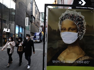 caption: South Korea's KF94 mask does a good job concealing Mona Lisa's smile — but how effective is it at preventing coronavirus spread? Above: masked pedestrians in a shopping district in Seoul.