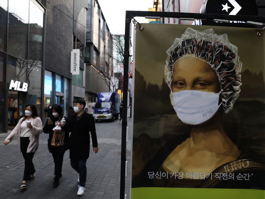 caption: South Korea's KF94 mask does a good job concealing Mona Lisa's smile — but how effective is it at preventing coronavirus spread? Above: masked pedestrians in a shopping district in Seoul.