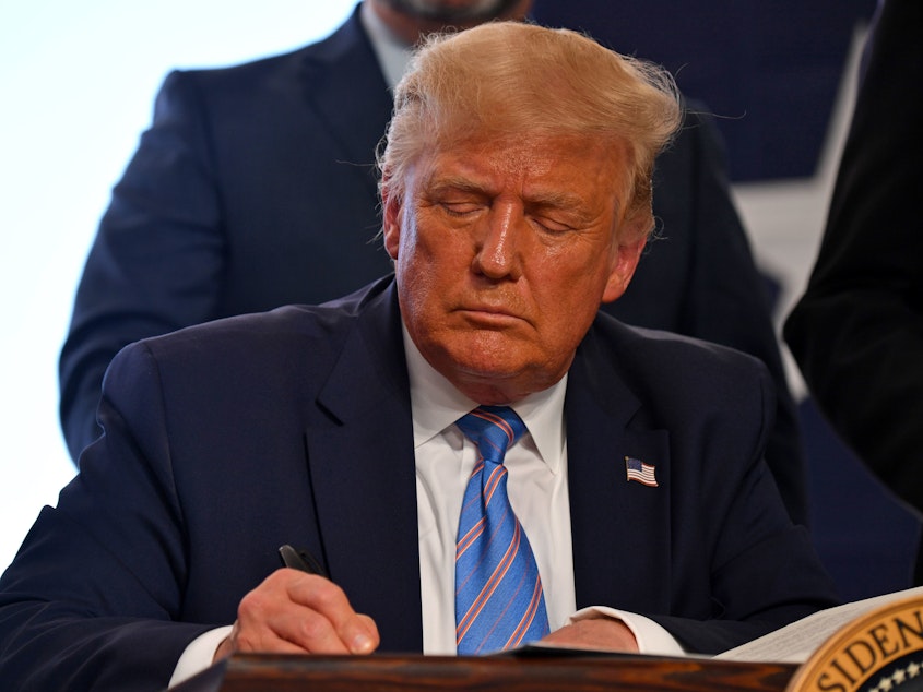 caption: President Trump signs energy permits in Midland, Texas, on Wednesday.