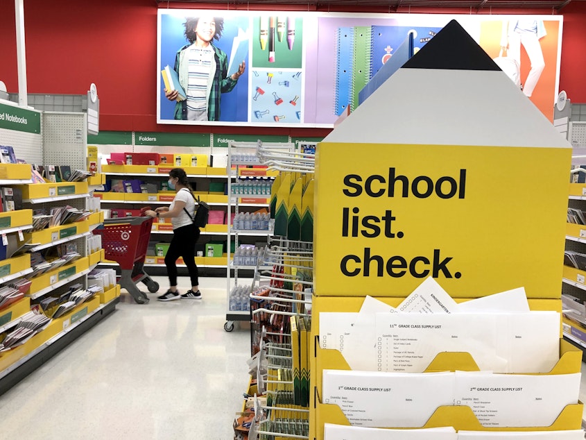 caption: A shopper walks past shelves of school supplies at a Target store in San Rafael, Calif. Preparing for both in-person and virtual learning has families budgeting for new school supplies and bigger purchases.