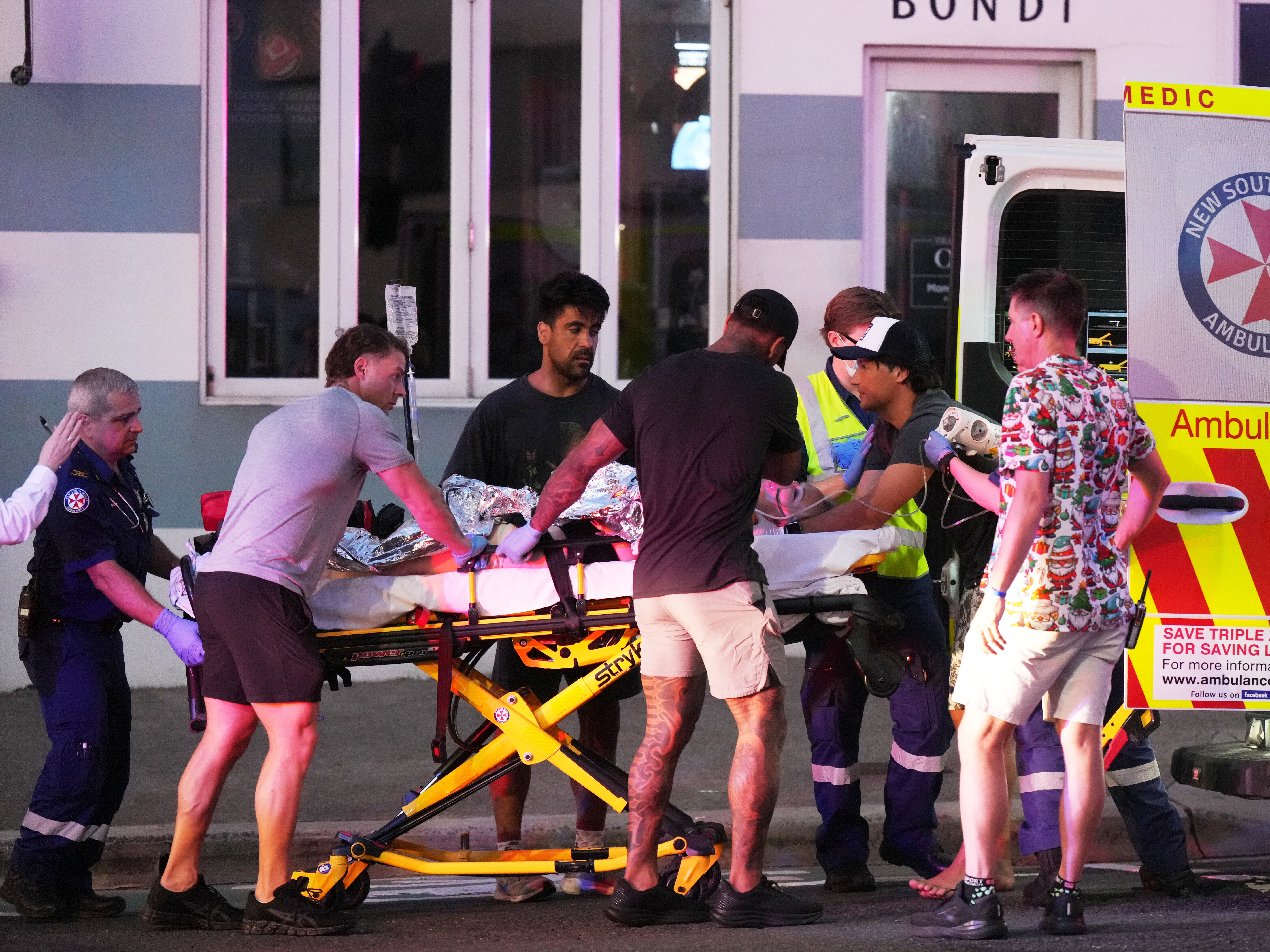 caption: Emergency workers transport a person on a stretcher after a reported shooting at Bondi Beach in Sydney on Sunday.