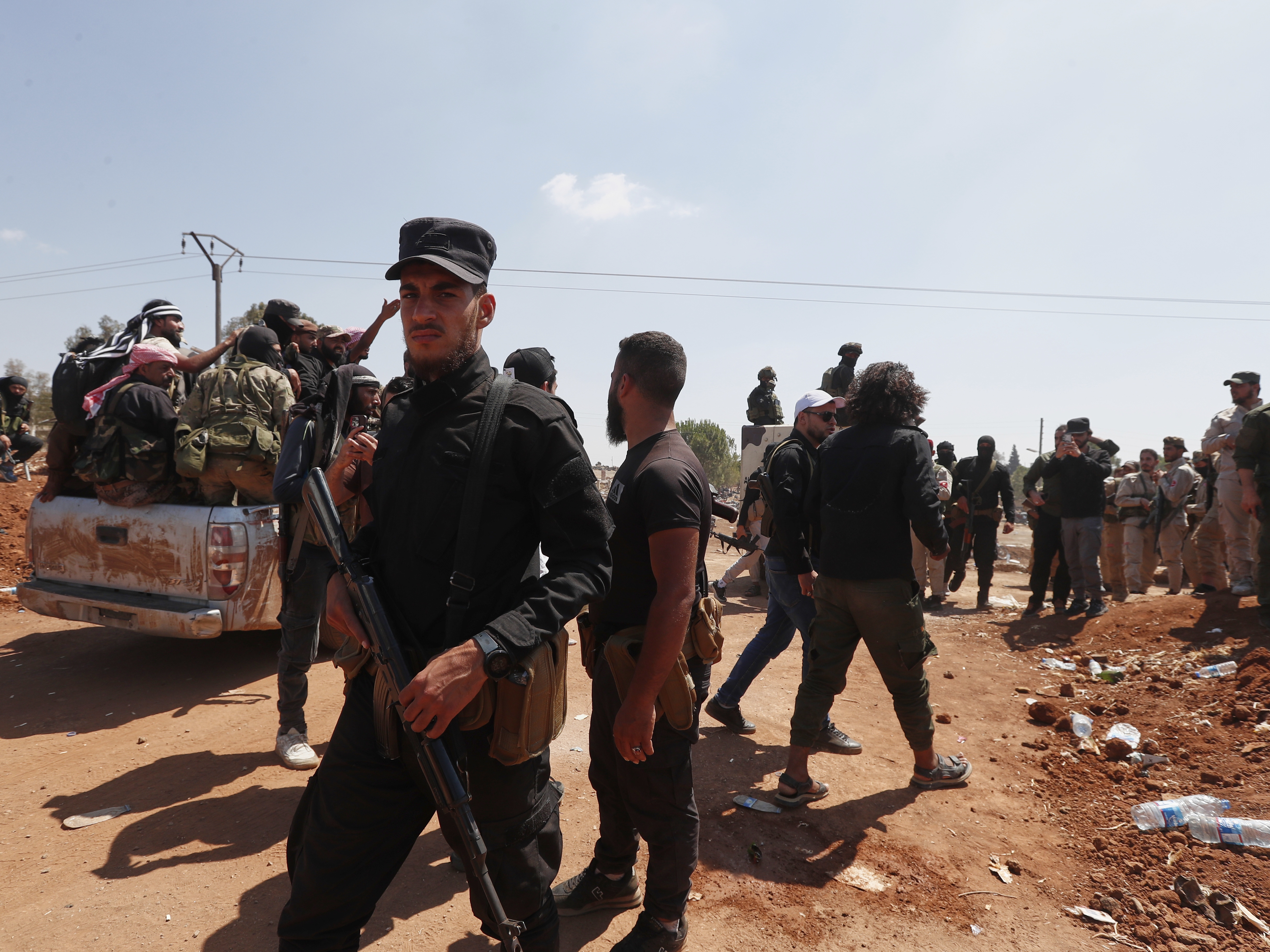 caption: Syrian government security forces block Bedouin fighters, background, from entering Sweida province, in Busra al-Harir village, southern Syria on Sunday.