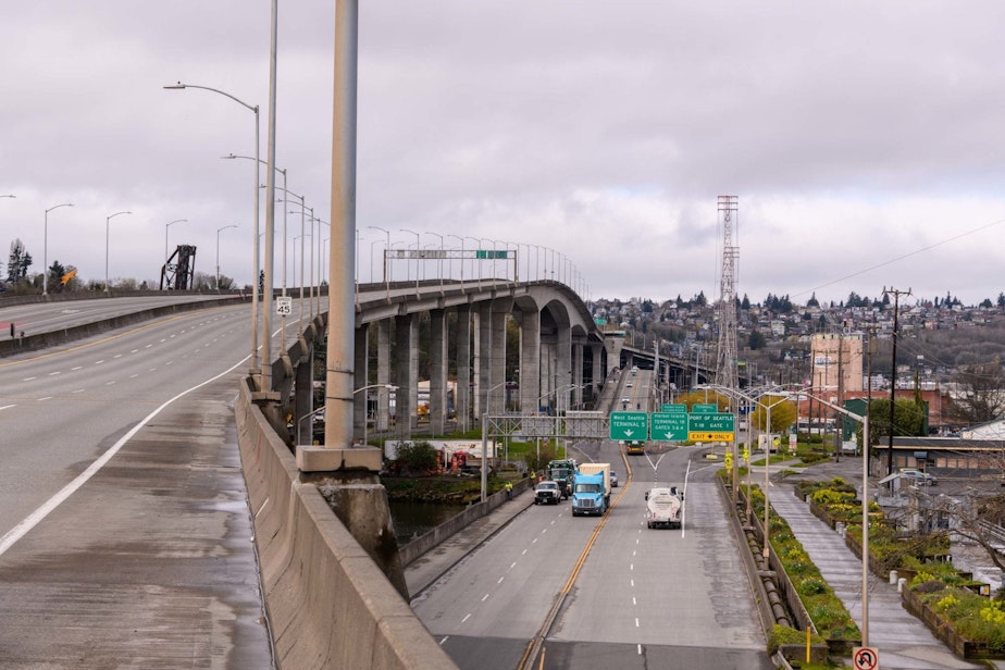 caption: The West Seattle Bridge, closed since March, rises above the Spokane Street Bridge across the Duwamish River.