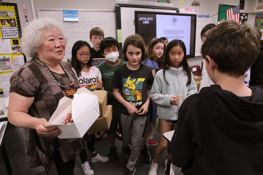 caption: Judy Kusakabe hands out paper cranes to a class of fourth-graders at West Mercer Elementary School on Mercer Island.
