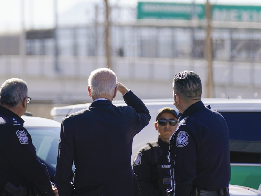 caption: President Biden looks toward a large "Welcome to Mexico" sign that is hung over the Bridge of the Americas as he tours the port of entry in El Paso Texas on Jan. 8.