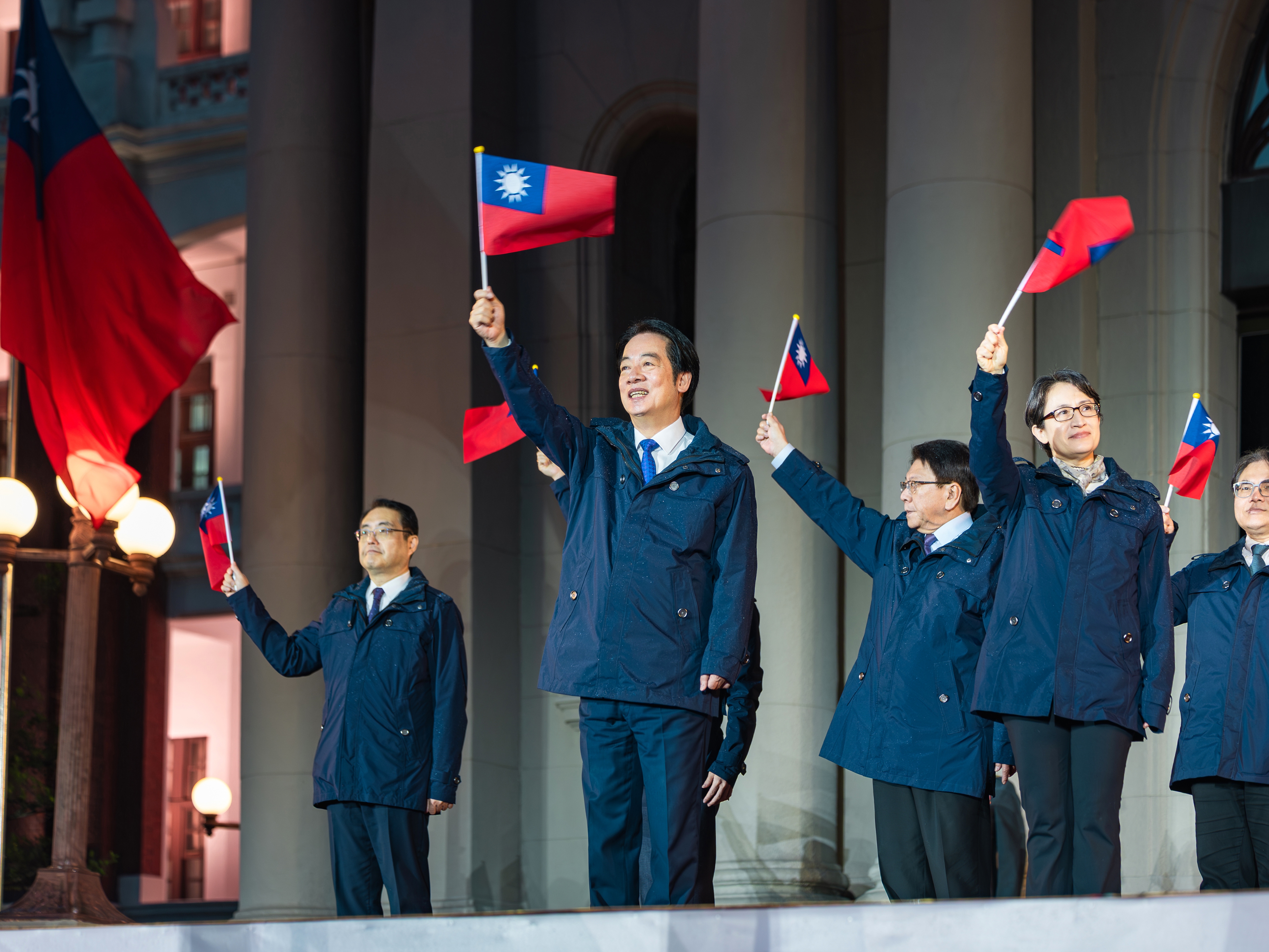 caption: In this photo released by the Taiwan Presidential Office, Taiwanese President Lai Ching-te (center) is accompanied by his Vice President Bi-Khim Hsiao (second right) and officials wave national flags as they attend a New Year flag raising ceremony at the Presidential Office, in Taipei, Taiwan, on Thursday, Jan. 1.