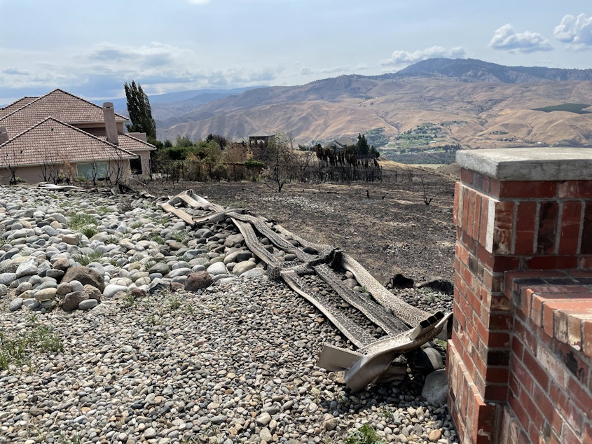 caption: The scorched remains of a yard in the Warm Springs Canyon neighborhood of Wenatchee. Fire breaks like rocks and fire-resistant plants saved many homes in the area from the Red Apple Fire.