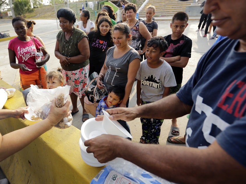 caption: Migrants seeking asylum in the United States receive breakfast from a group of volunteers near the international bridge in Matamoros, Mexico.