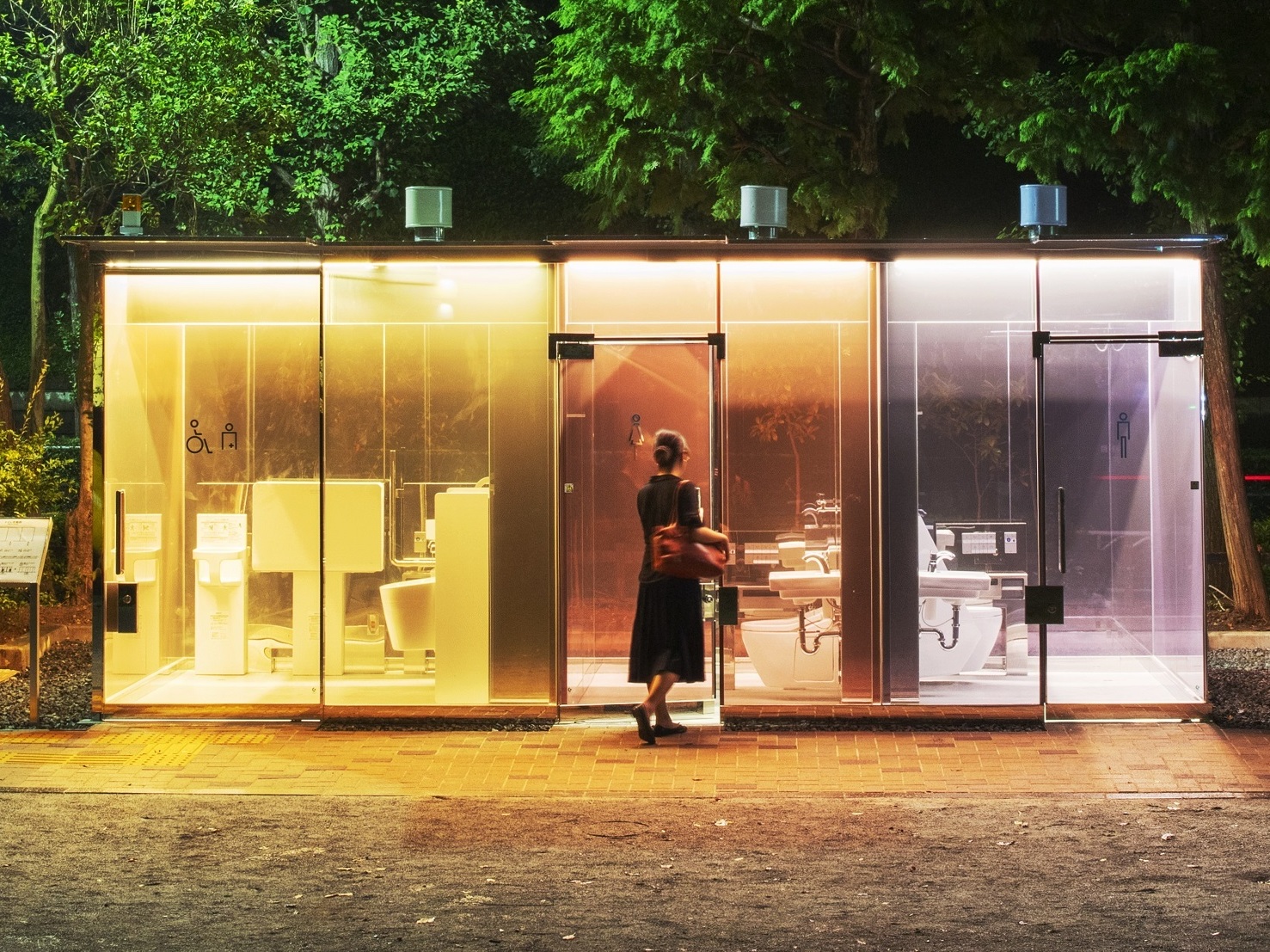 caption: A woman enters a public restroom with transparent walls in Tokyo's Shibuya ward. Architect Shigeru Ban designed the bathroom in a way to reassure anyone entering the toilet.