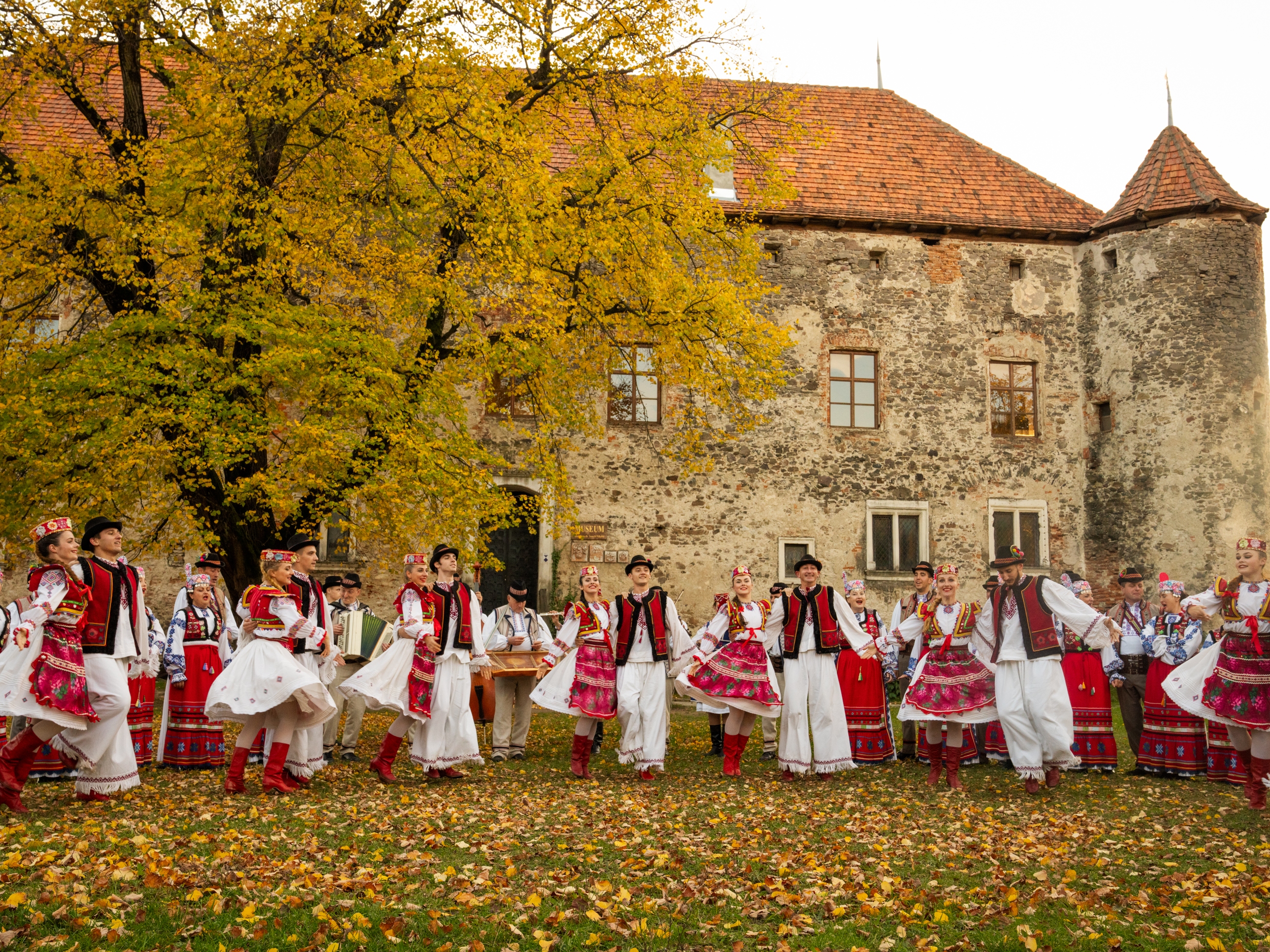 caption: The Transcarpathian Folk Choir performs a song and dance for a music video that they are working on to share their music. Ukraine's St. Miklos Castle, which is now an arts exhibit space, a meeting place and museum for local history, provides the backdrop.