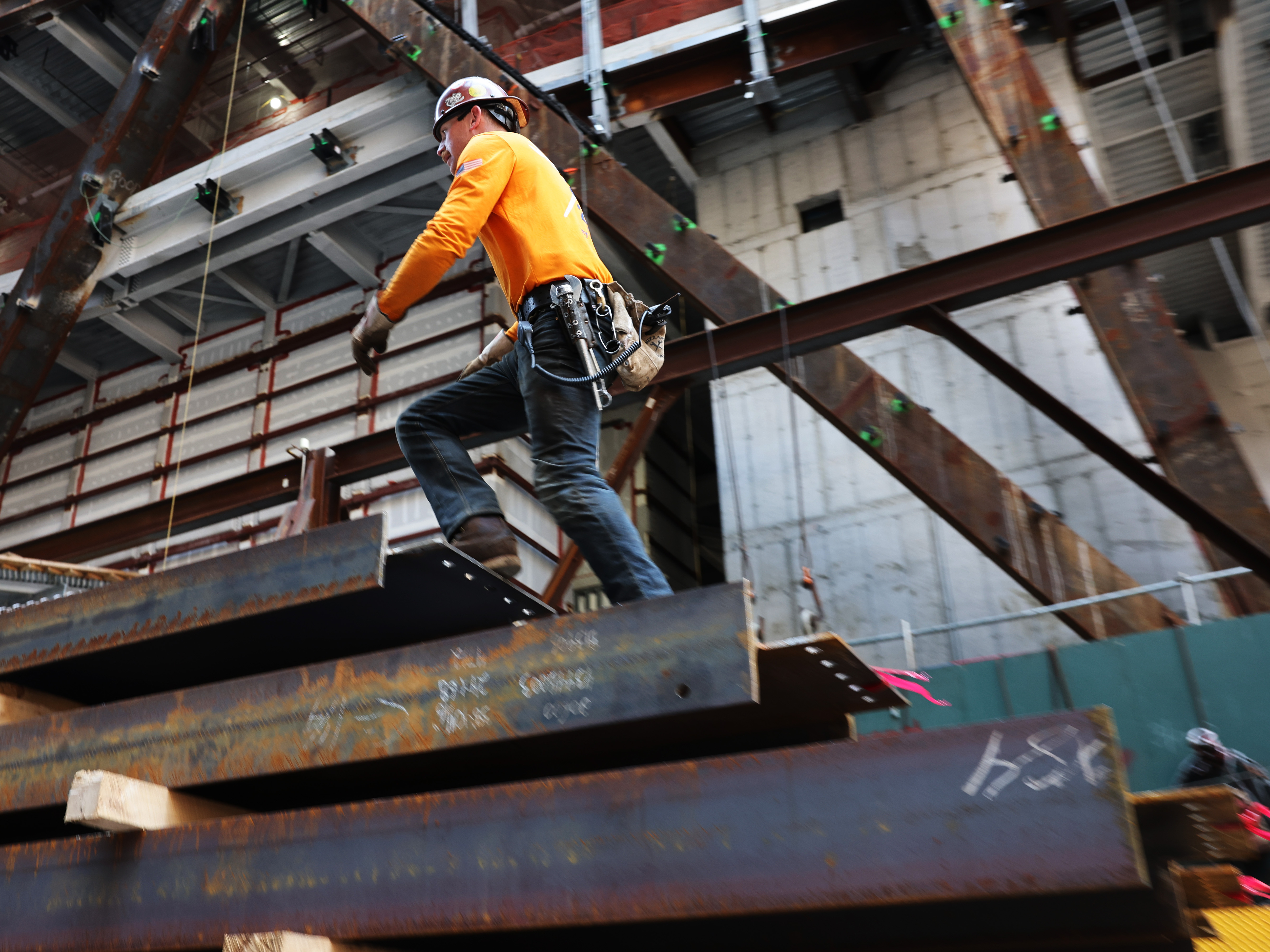 caption: Construction workers prepare steel for a crane at construction site in New York City on May 18, 2023.