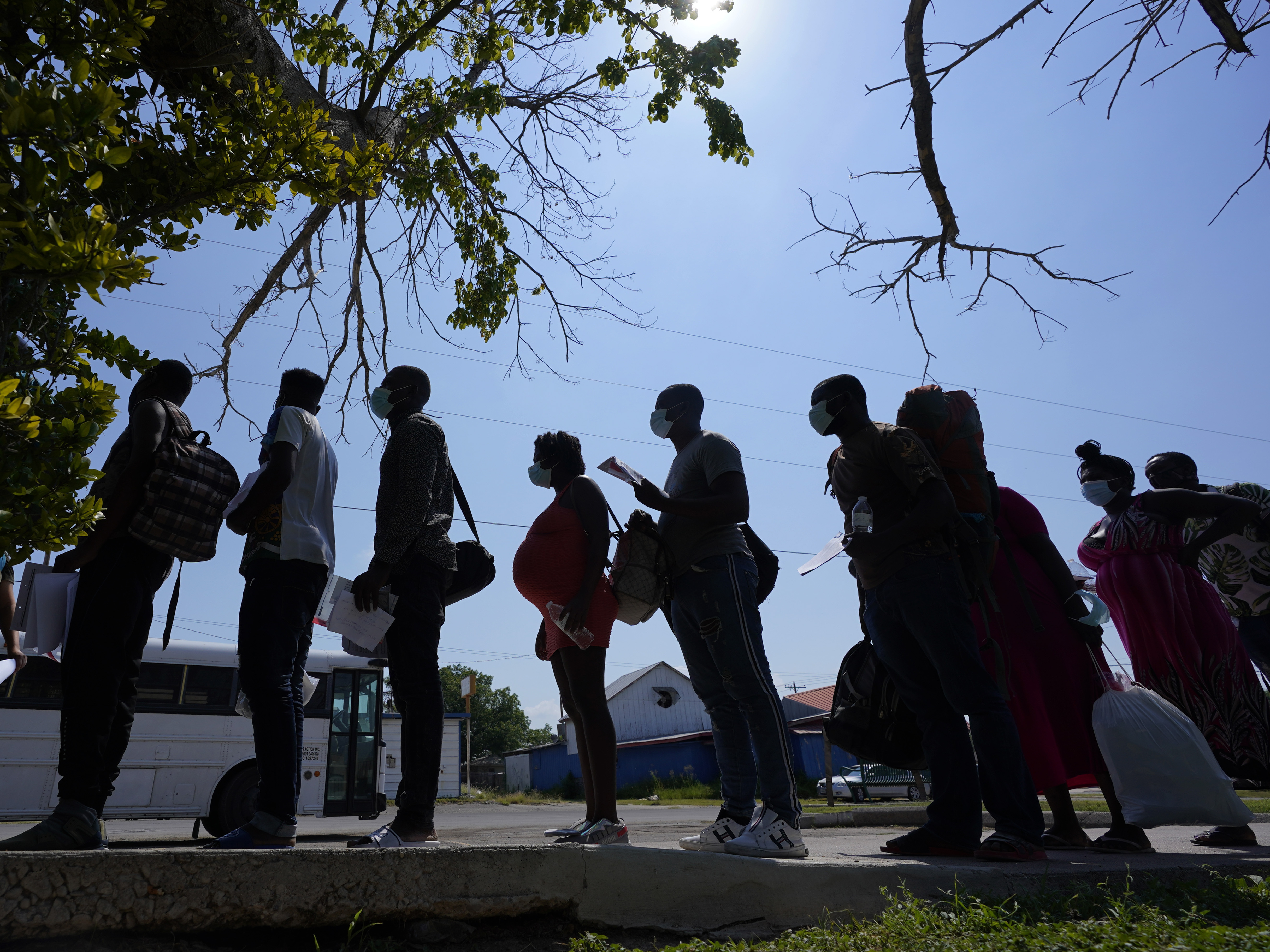 caption: Migrants stand in line at a respite center in June after they crossed the U.S.-Mexico border and turned themselves in and were released in Del Rio, Texas.