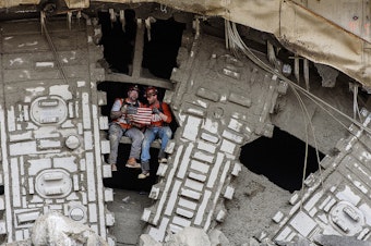 caption: Members of Bertha's crew pose after the tunneling machine broke into the disassembly pit, near Seattle's Space Needle, on April 4, 2017.