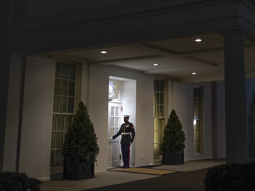 caption: A Marine stands outside the entrance to the West Wing of the White House, signifying President Donald Trump is in the Oval Office, on Thurs., Jan. 7, 2021.