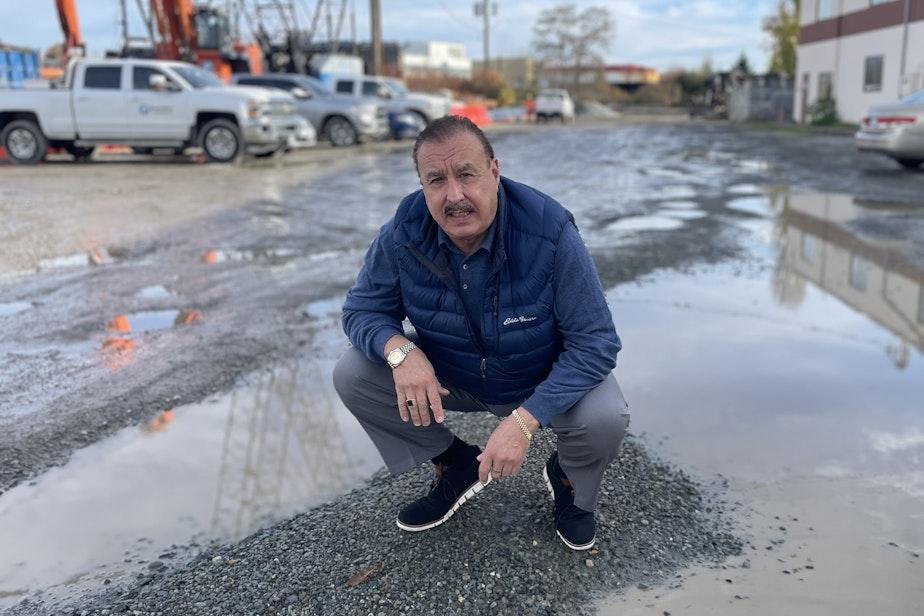 caption: Carlos Gonzalez in the flood-ravaged gravel road outside his business