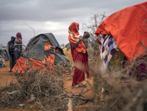 caption: A woman breastfeeds her child at a camp for displaced people in Somalia, where climate change is fueling severe drought.