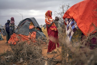 caption: A woman breastfeeds her child at a camp for displaced people in Somalia, where climate change is fueling severe drought.