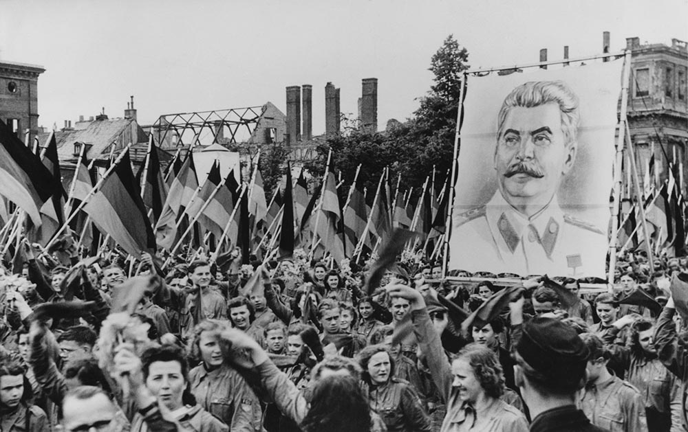 caption: A Soviet-sponsored youth rally in the Lustgarten in Berlin, Germany, 1st June 1950. The youth carry huge portraits of Communist leaders such as Joseph Stalin (pictured). (FPG/Getty Images)