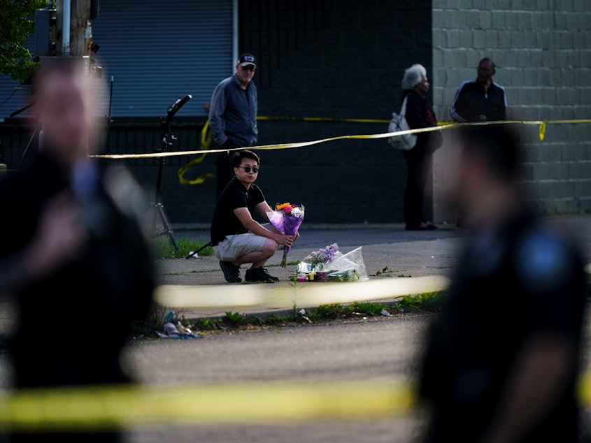 caption: A person places flowers outside the scene of the mass shooting at a supermarket in Buffalo, N.Y., on Sunday.