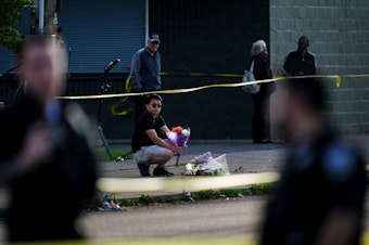caption: A person places flowers outside the scene of the mass shooting at a supermarket in Buffalo, N.Y., on Sunday.