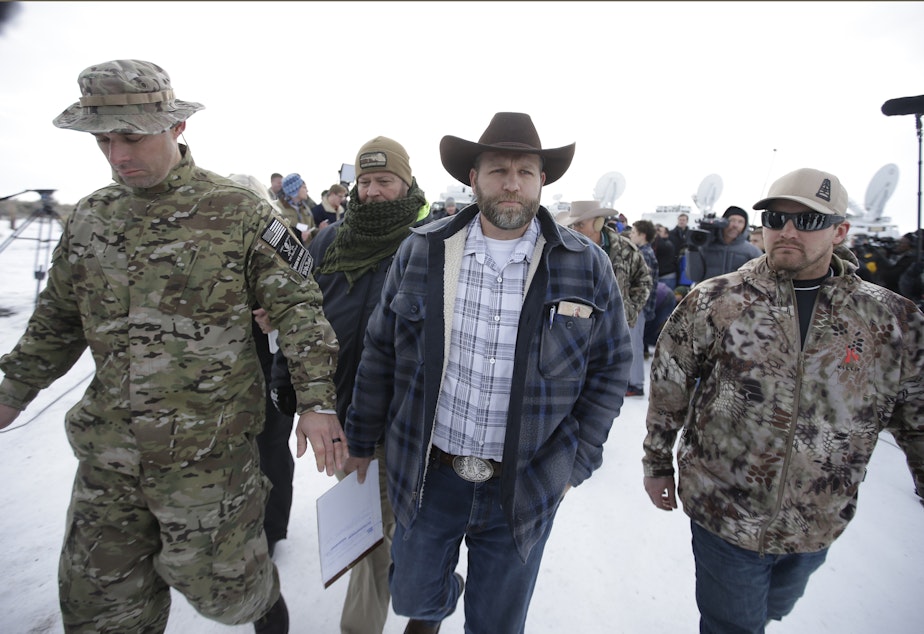 caption: Ammon Bundy, center, one of the sons of Nevada rancher Cliven Bundy, walks off after speaking with reporters during a news conference at Malheur National Wildlife Refuge headquarters Monday, Jan. 4, 2016, near Burns, Ore.