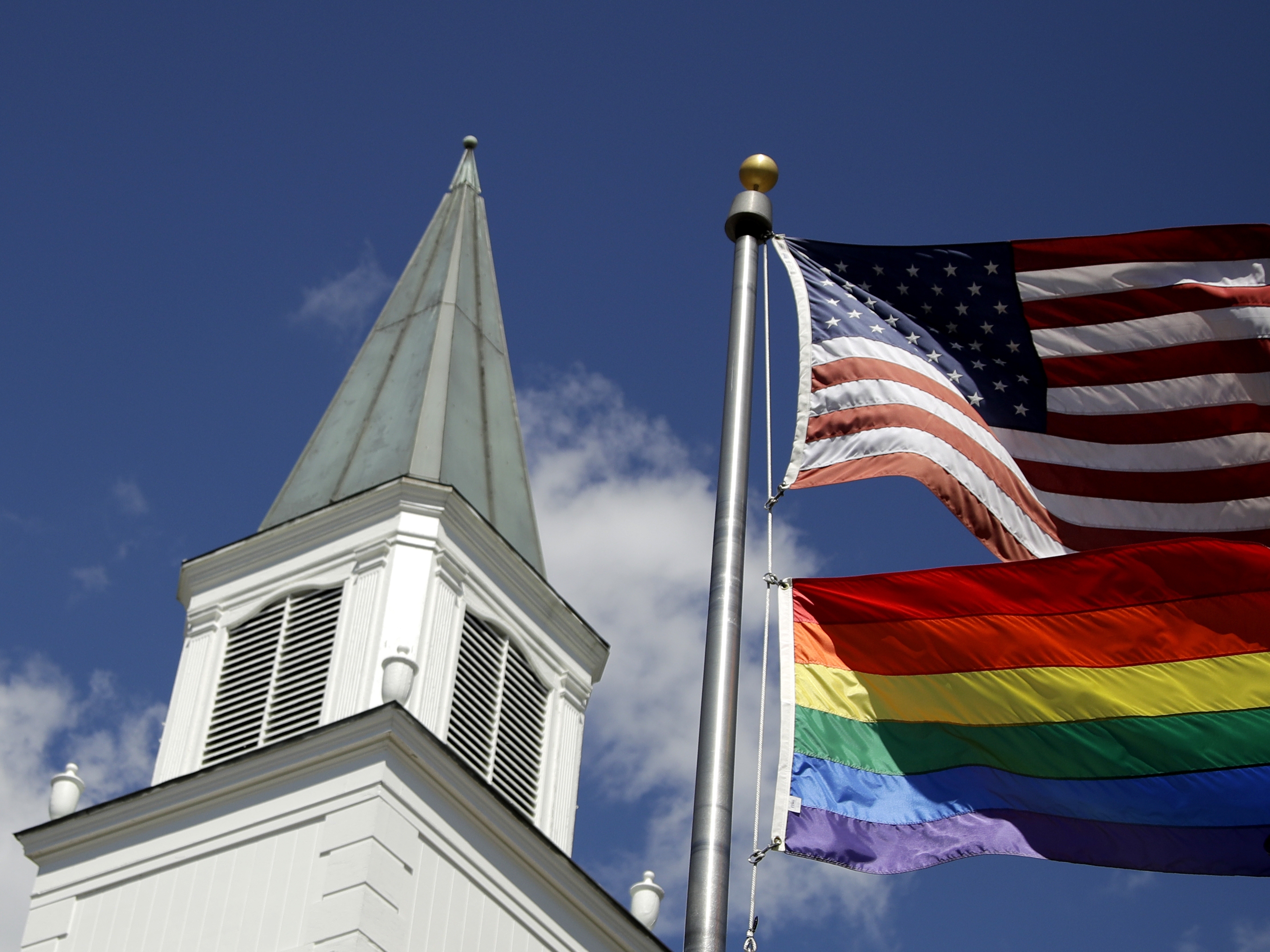 caption: A gay pride rainbow flag flies along with the U.S. flag in front of the Asbury United Methodist Church in Prairie Village, Kan.