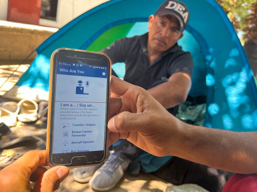 caption: A migrant in Ciudad Juárez, Mexico, displays the CBP One app used to apply for an appointment to claim asylum in the U.S.