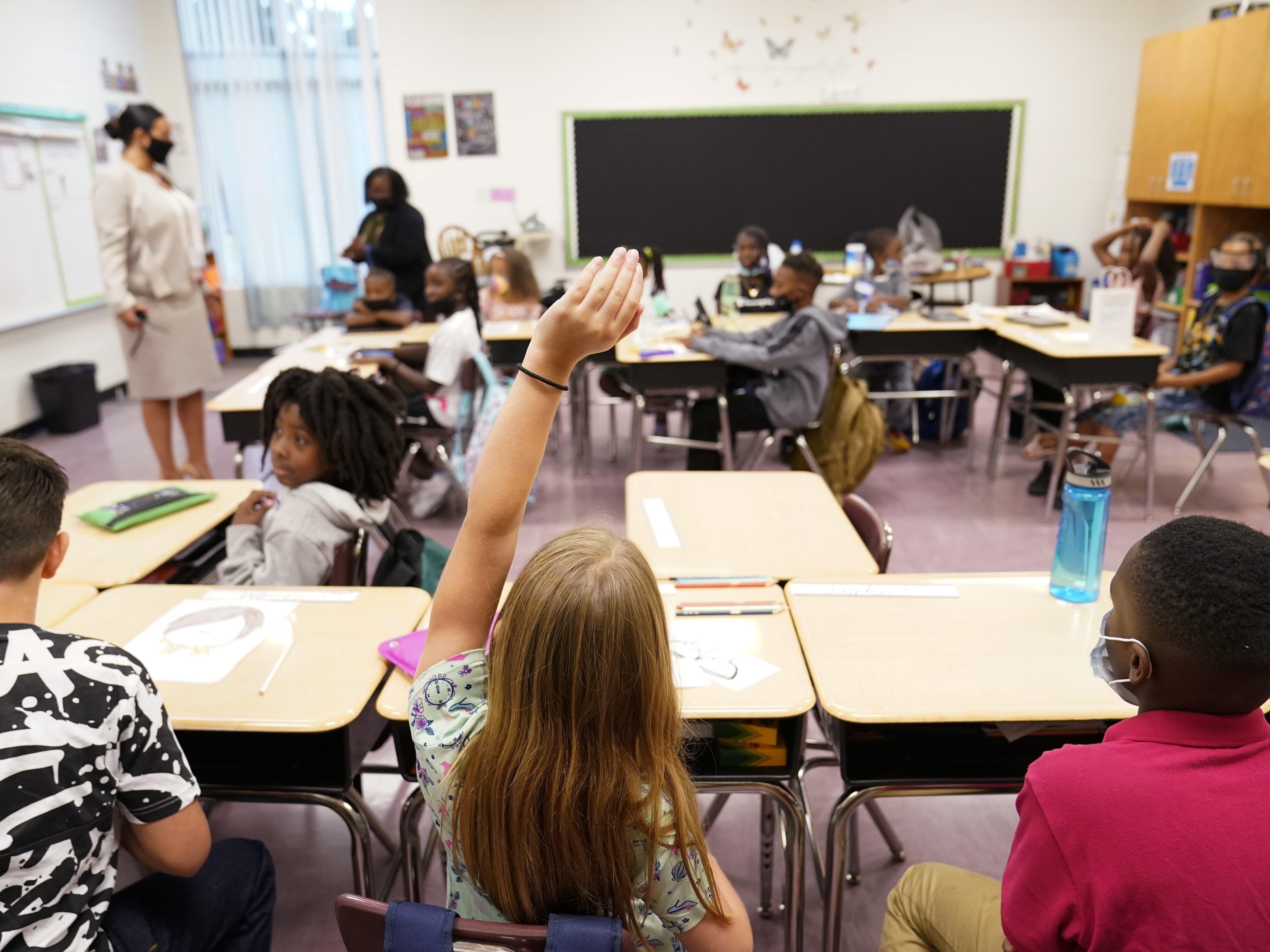 caption: A student raises their hand in a classroom at Tussahaw Elementary School in 2021 in McDonough, Ga.
