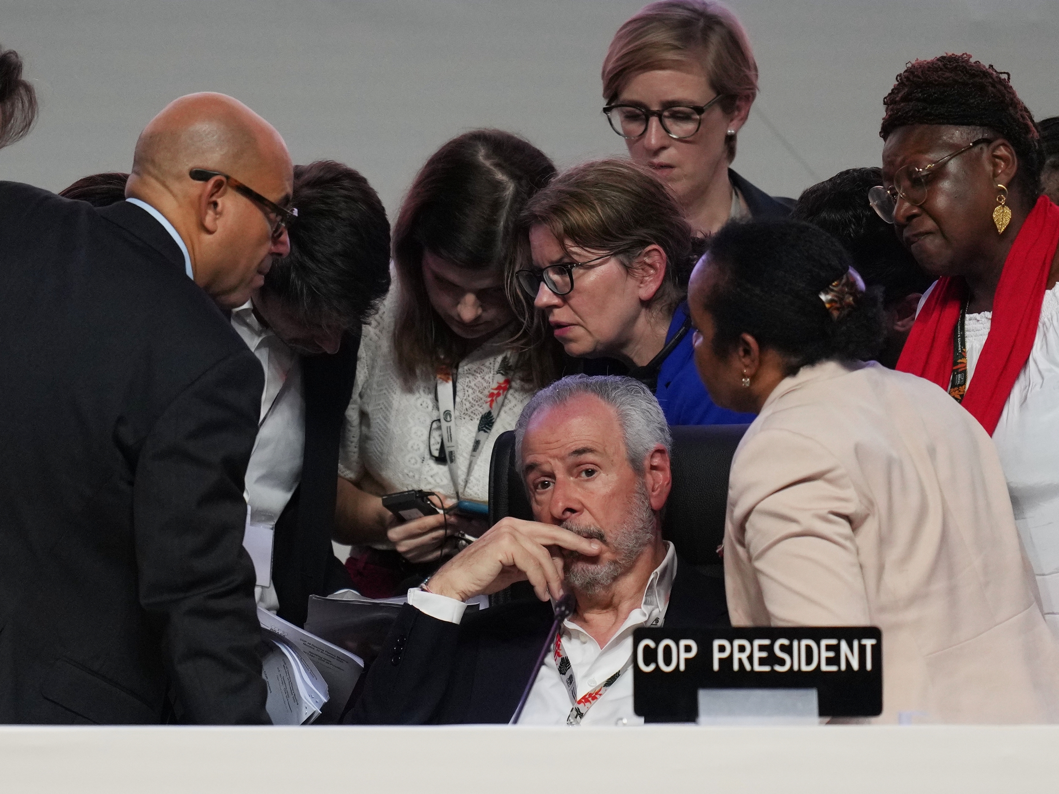 caption: André Corrêa do Lago, center, the president of the COP30 climate conference in Brazil, sat as negotiators huddled in last-minute deliberations on Saturday.