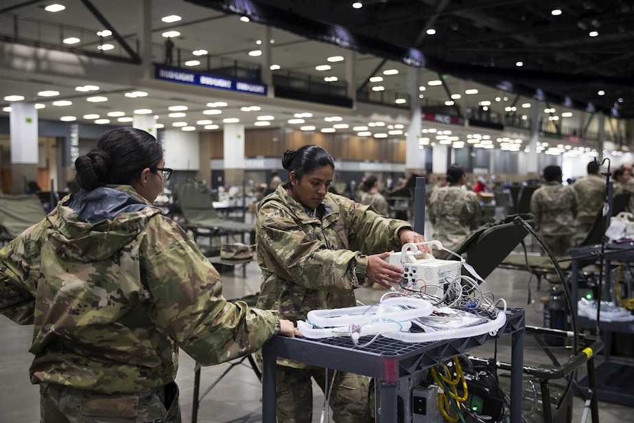 caption: U.S. Army soldiers Viviana Alvarez, left, and Maria Cuevas, right, from the 627th Army Hospital from Fort Carson, Colorado, set up patient monitors in the ICU area of a 250-bed military field hospital being deployed alongside soldiers from Joint Base Lewis-McChord on Tuesday, March 31, 2020, at the CenturyLink Field Event Center in Seattle. The hospital will be for non COVID-19 patients. 