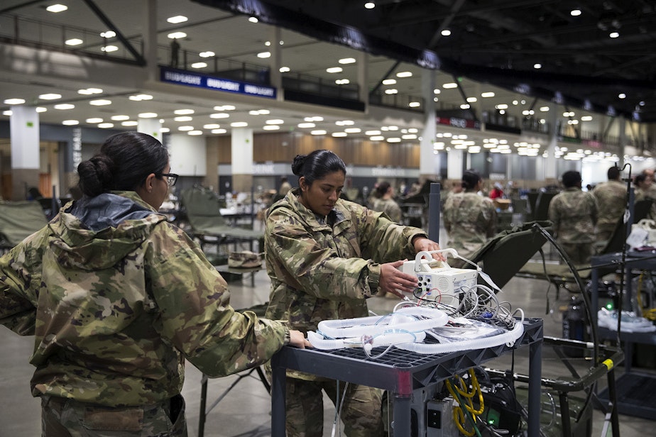 caption: U.S. Army soldiers Viviana Alvarez, left, and Maria Cuevas, right, from the 627th Army Hospital from Fort Carson, Colorado, set up patient monitors in the ICU area of a 250-bed military field hospital being deployed alongside soldiers from Joint Base Lewis-McChord on Tuesday, March 31, 2020, at the CenturyLink Field Event Center in Seattle. The hospital will be for non COVID-19 patients.