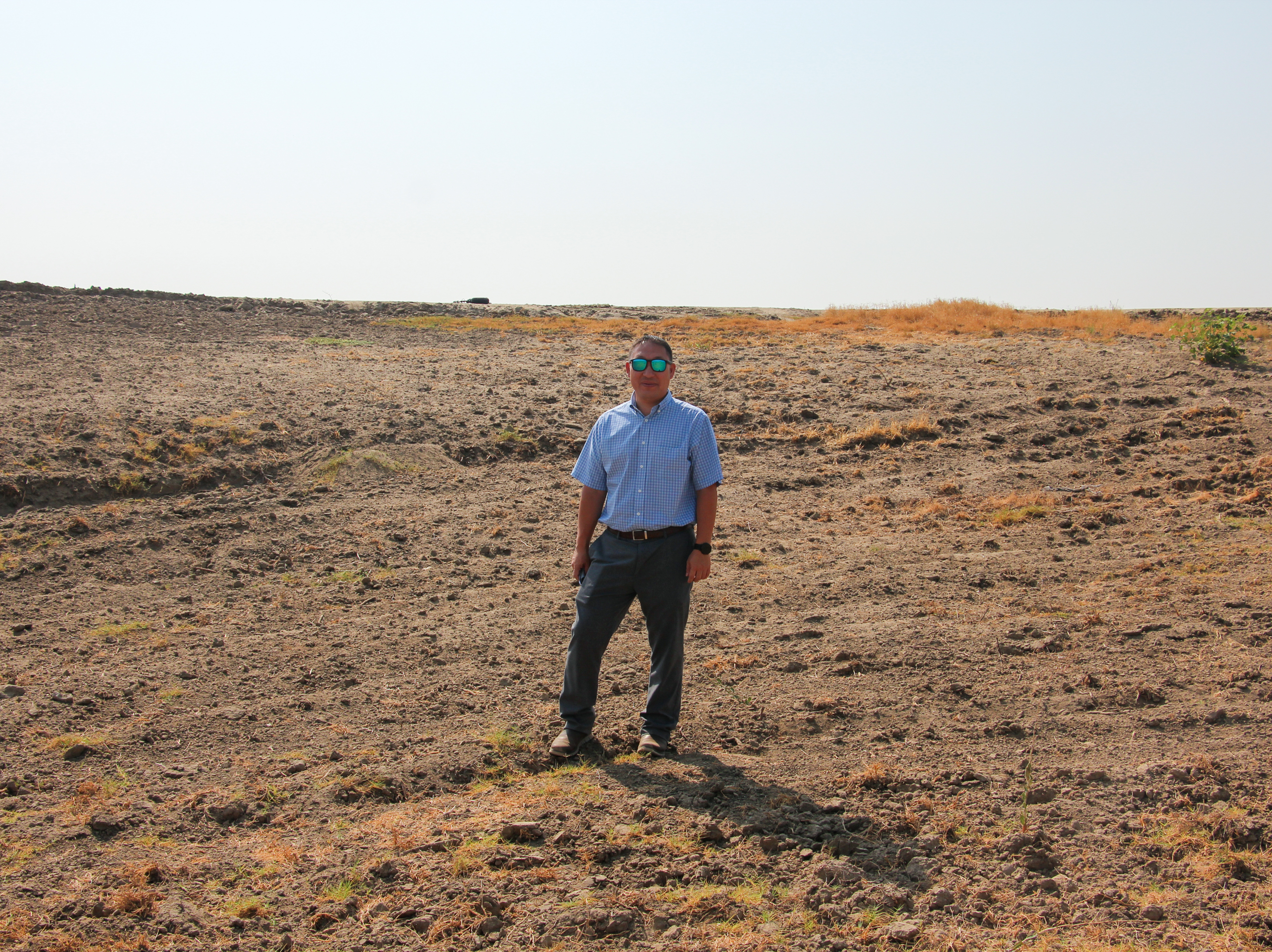 caption: Aaron Fukuda, general manager of Tulare Irrigation District, stands in a basin that's designed to capture floodwater so that it can replenish depleted aquifers.