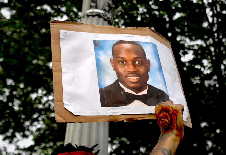 caption: A person protesting racial injustice holds a photo of Ahmaud Arbery during a May 2020 march in Washington, D.C.