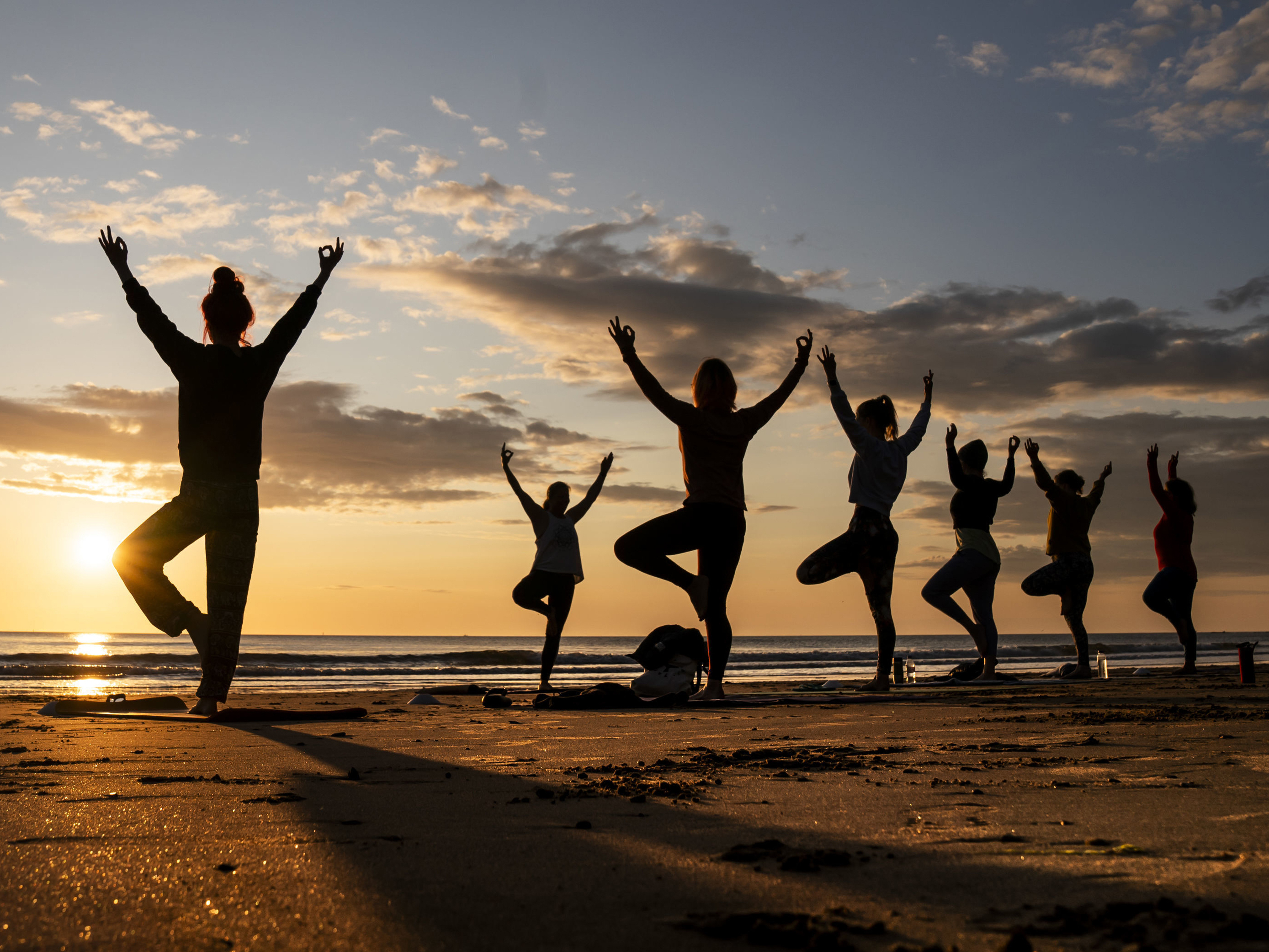 caption: Members of the Happy Seal Yoga class practice on Cayton Bay in Scarborough as the sun rises to celebrate the Summer Solstice, Wednesday June 21, 2023.