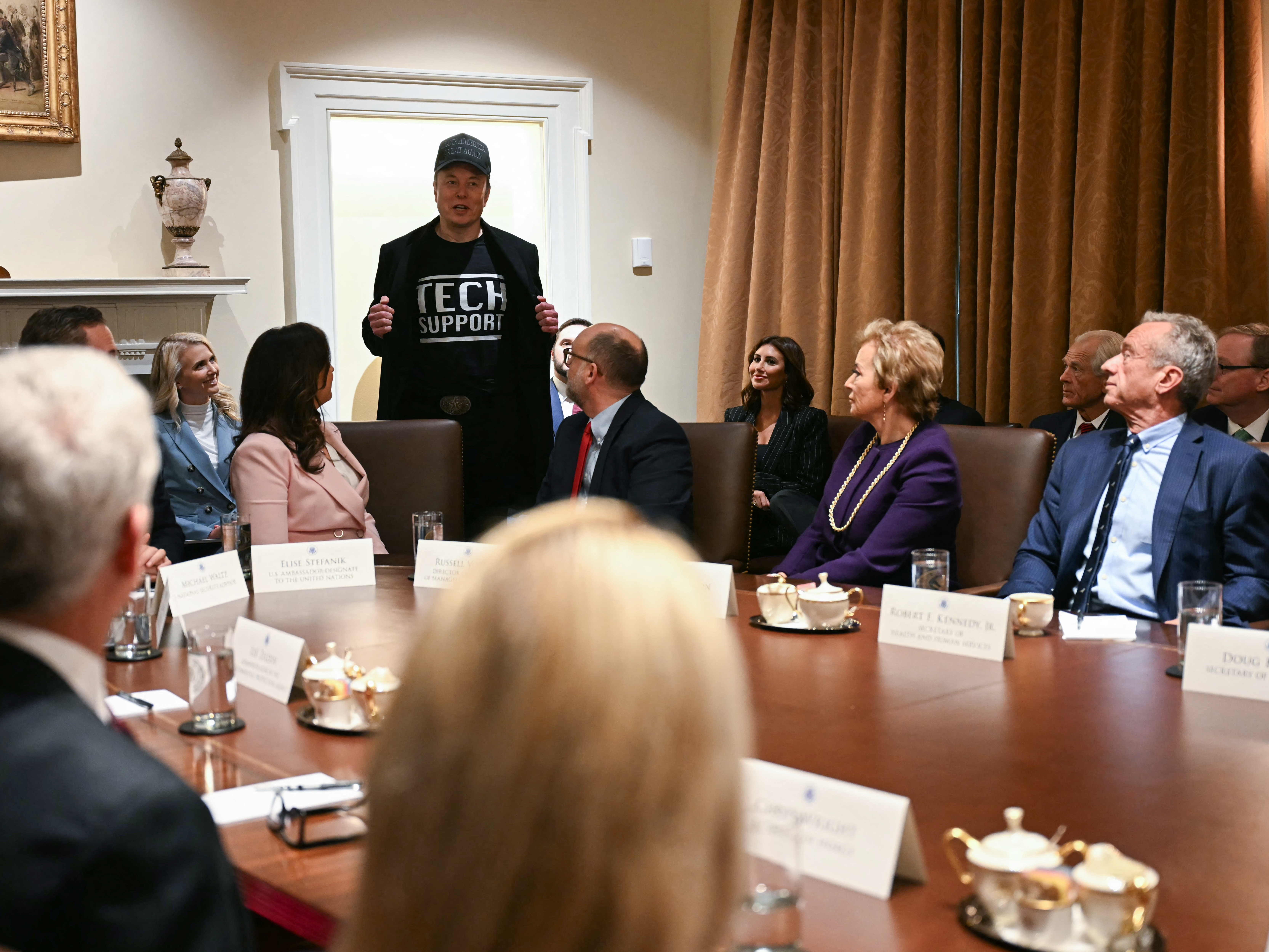 caption: Leader of the Department of Government Efficiency Elon Musk wears a shirt that says "Tech Support" as he speaks during a cabinet meeting with US President Donald Trump at the White House in Washington, DC, on February 26, 2025.
