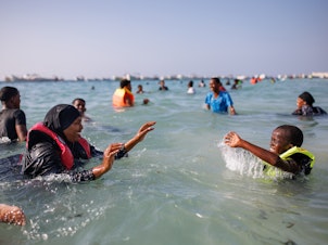 caption: A mother and her son play in the sea at Liido Beach in Mogadishu, Somalia. Despite decades of conflict and ongoing security threats, some Somalis are carving out a middle-class lifestyle in the Somali capital.