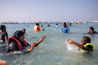 caption: A mother and her son play in the sea at Liido Beach in Mogadishu, Somalia. Despite decades of conflict and ongoing security threats, some Somalis are carving out a middle-class lifestyle in the Somali capital.