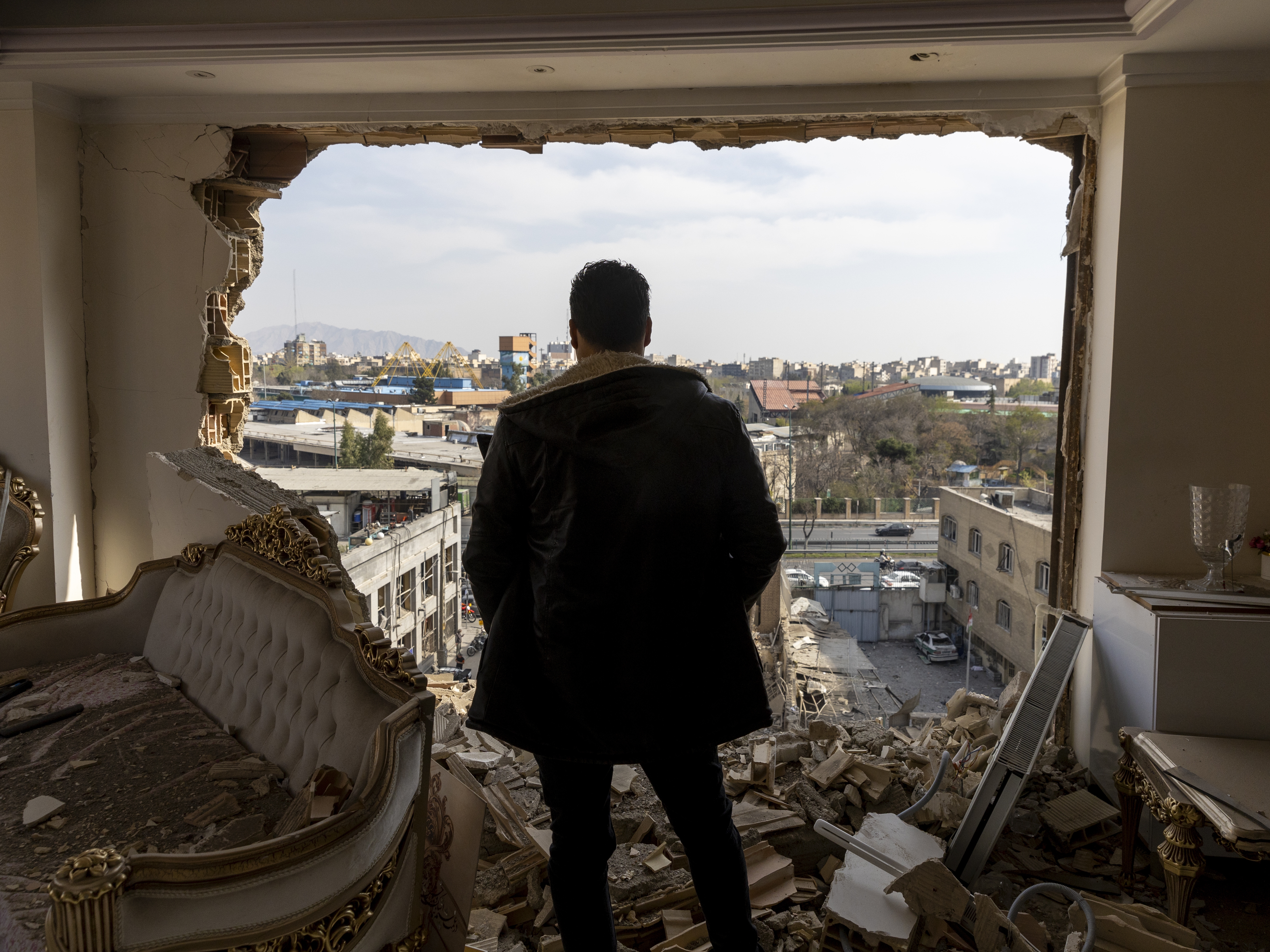 caption: A man stands in a damaged residence in Tehran on March 14.
