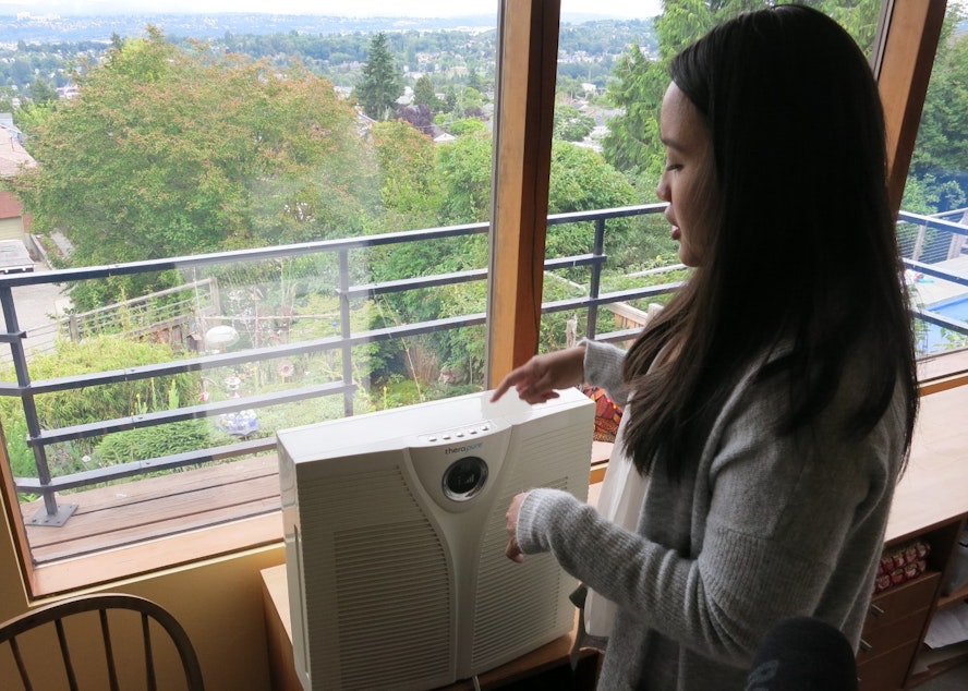 caption: Xamantha Curameng with the American Lung Association inspects the Pliskes' living room air purifier during a home visit, July 2nd, 2019. 