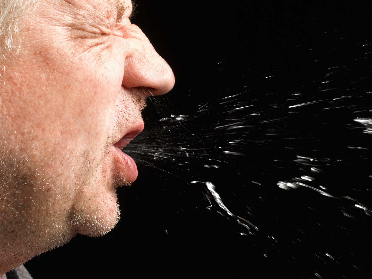 caption: A sneeze can carry the coronavirus pathogen in droplets and in aerosols — and they could land on a surface, making it a fomite.